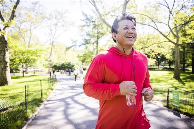 Man jogging outside, listening to something through earbuds and carrying a water bottle Man jogging outside, listening to something through earbuds and carrying a water bottle