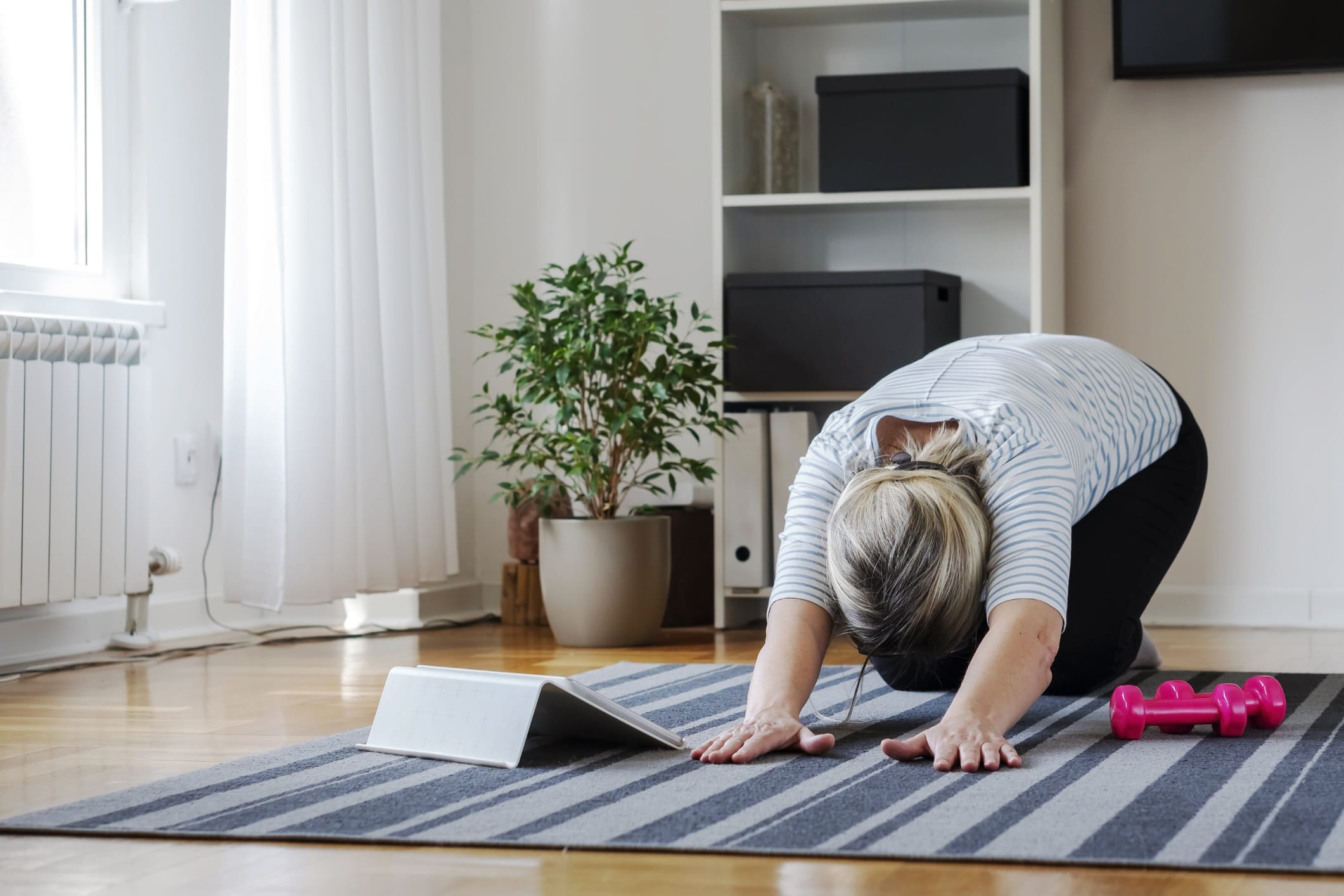 Senior woman following tutorial online and exercise at home