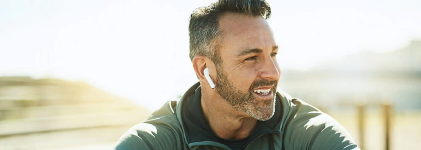 Shot of a mature man using wireless earphones while out for his workout