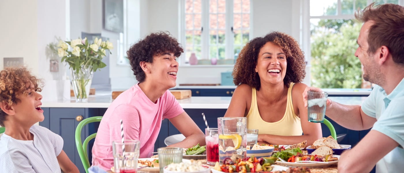 Family sitting around table at home eating meal together 