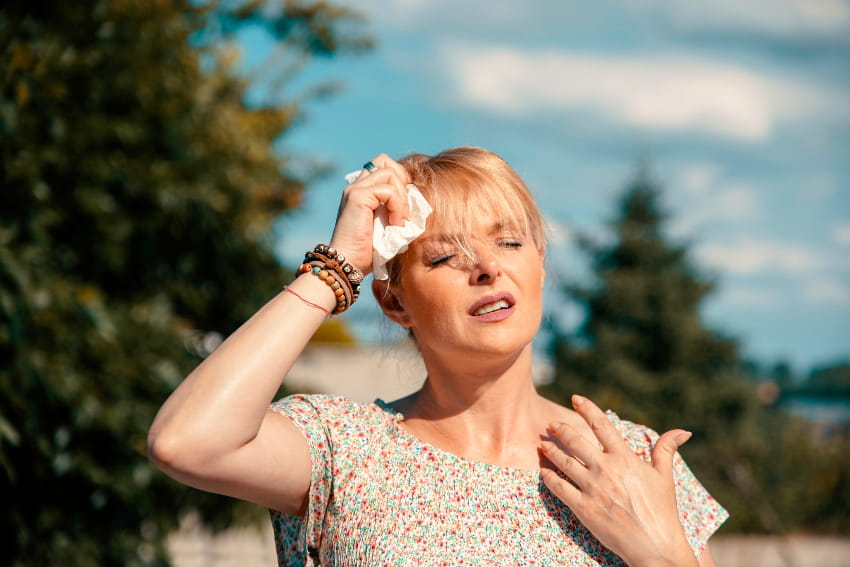 A woman outside experiencing a hot flash.