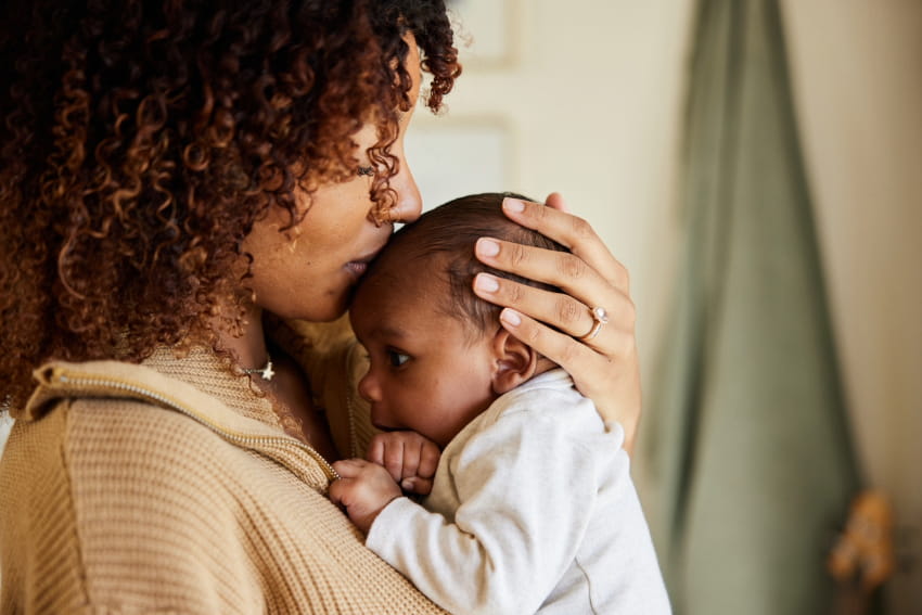 Mother kissing with her baby in her arms.
