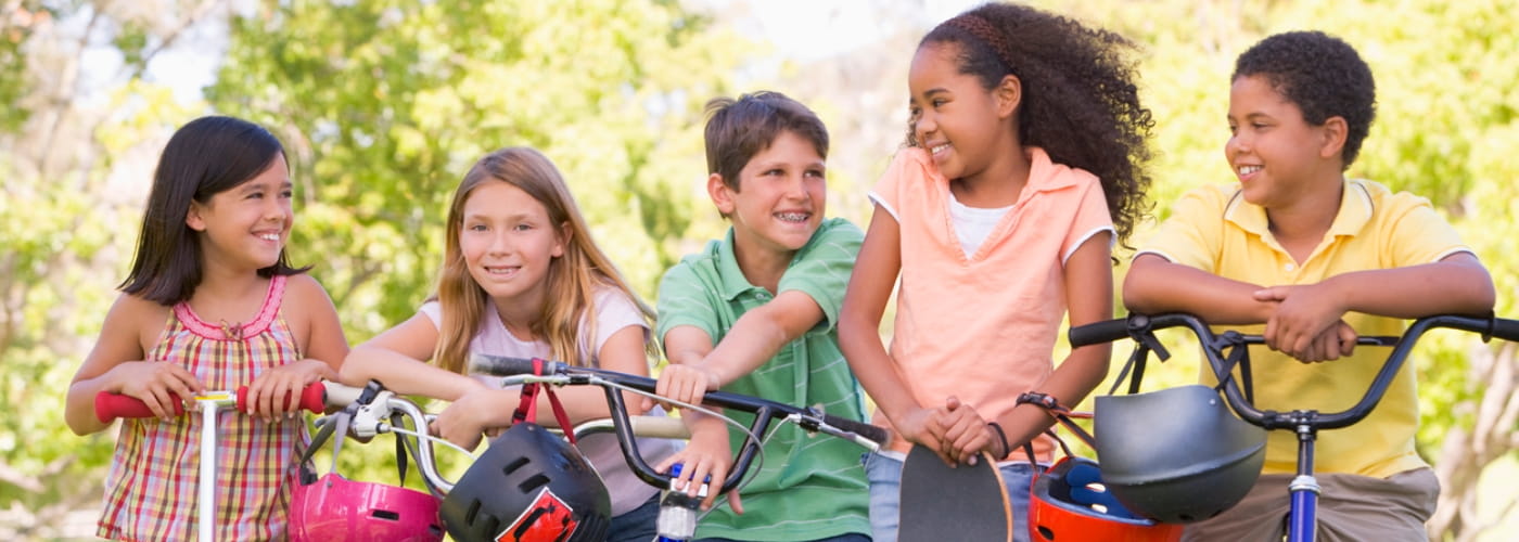 Five young friends with bicycles scooters and skateboard outdoors