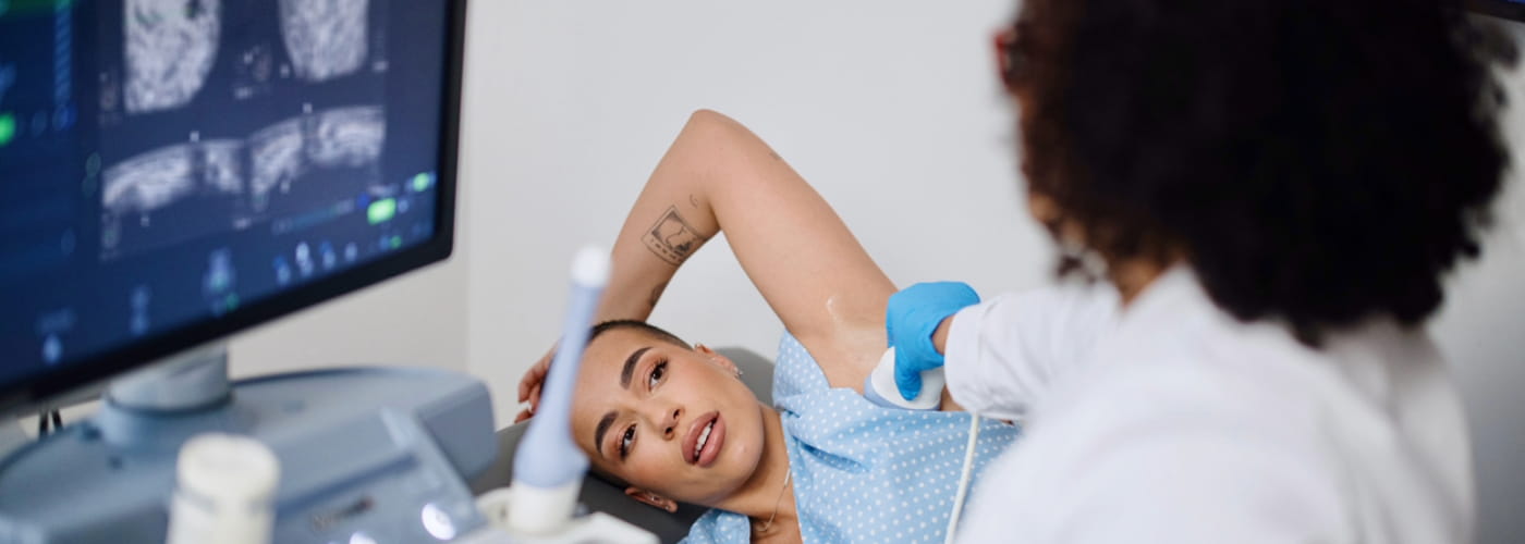 Woman in a doctors office having a breast ultrasound preformed. 