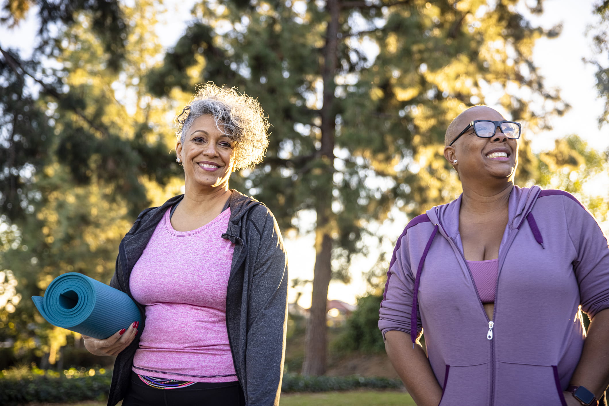 Two middle aged women walking outside with yoga mat