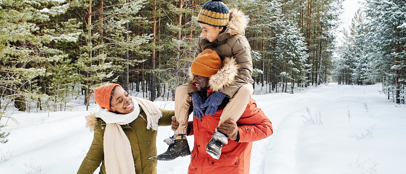 Young family of father, mother and son enjoying winter day in park