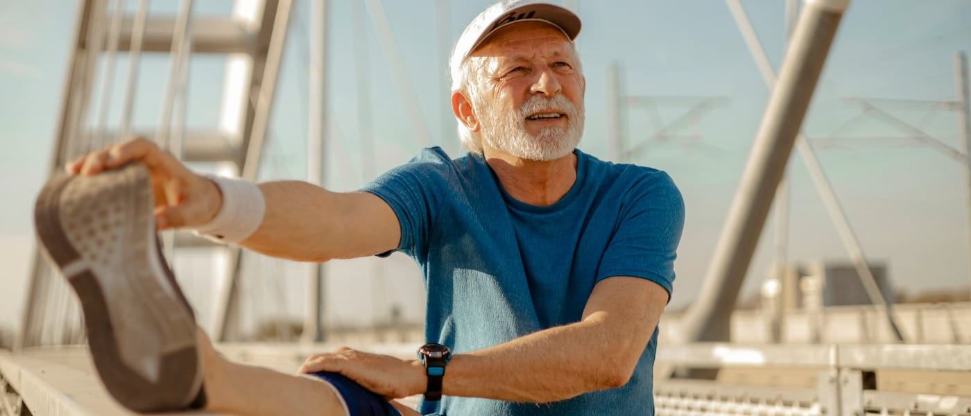Senior Man in Sportswear Outside Stretching His Leg Before Exercising