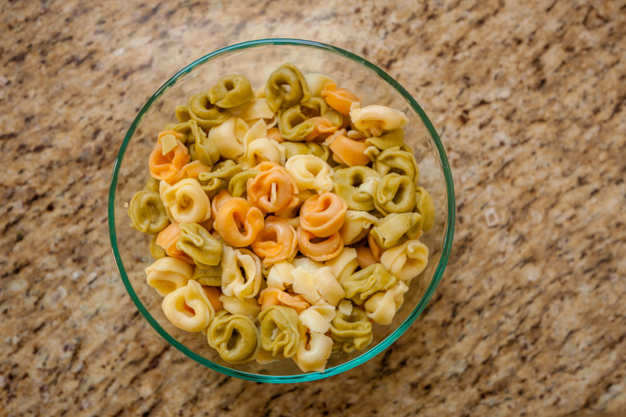 Cooked tri-color tortellini in a glass bowl.