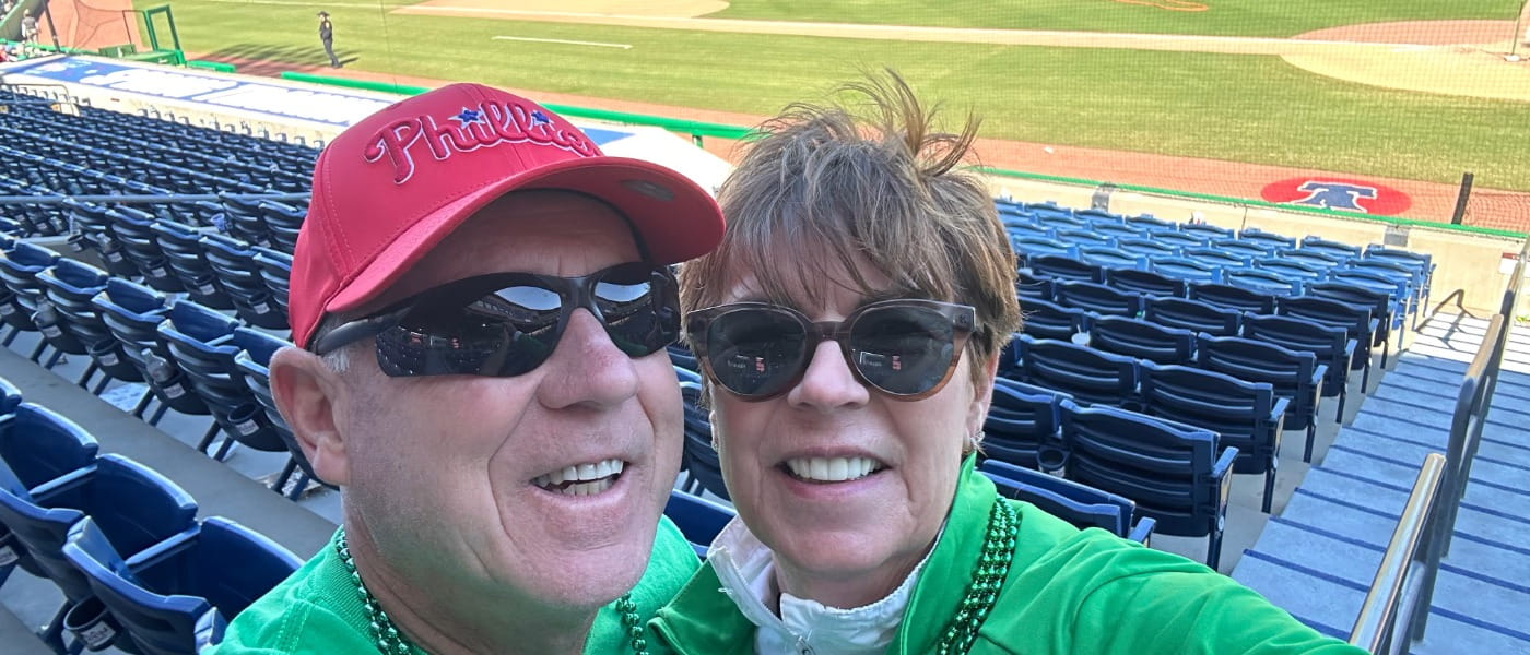 Vince and Kathie Gallagher posing in the stands of a the Phillies baseball field.