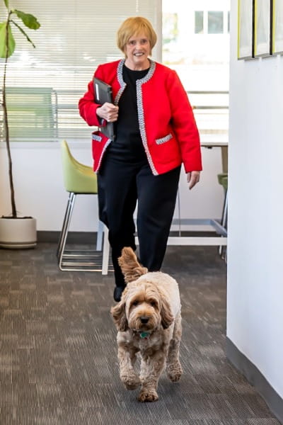 Celeste following her dog Marci for a walk down the hall of an office building.