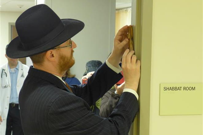 Man placing mezuzah on door frame of Shabbat Room