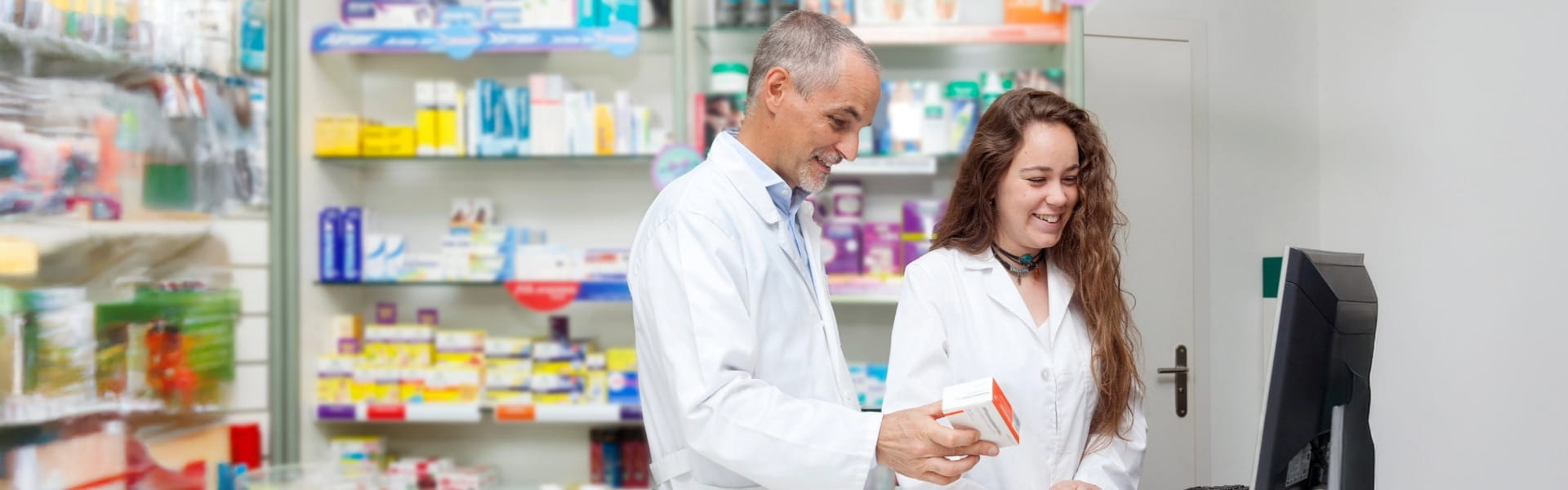 Pharmacists working together at computer in pharmacy