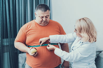 Large man being measured around waist by health care provider Large man being measured around waist by health care provider