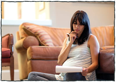 Pregnant woman sitting and thinking with pen and notebook Pregnant woman sitting and thinking with pen and notebook