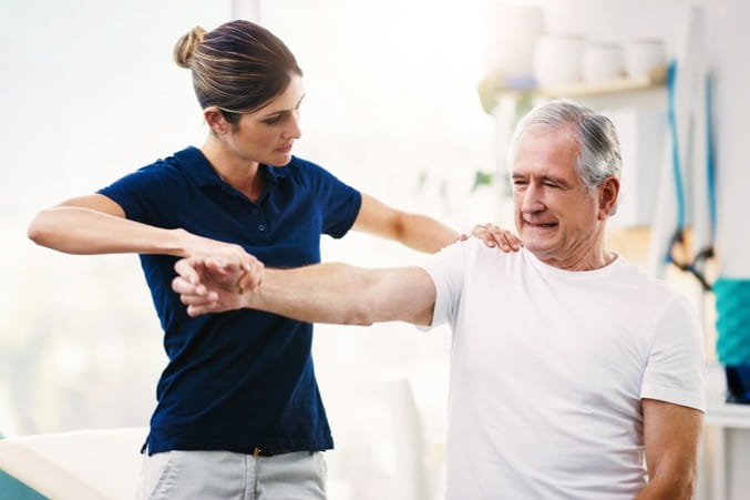 Therapist evaluating male patient's arm.