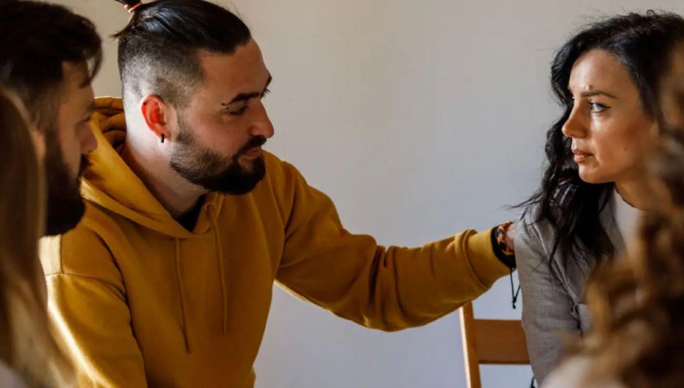 Man offering comfort to woman in group therapy